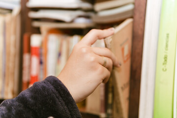 Book Day, April 23rd. Woman choosing a book in her home library. Comfort.