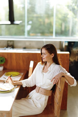 Smiling Woman Enjoying Romantic Dinner at Home A beautiful brunette woman sits at a trendy dining...
