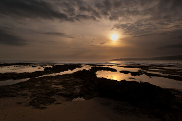 Puesta de sol playa de Sawarna, con arena piedras y reflejos. Labak Regency, Banten. Java, Indonesia