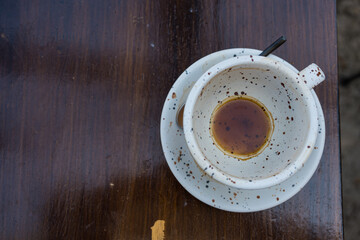 Close up empty coffee cups with stains left in the cups on the wooden table in street cafe on sunny morning