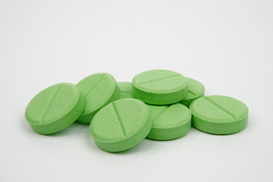 Heap of green antacid tablets against white background