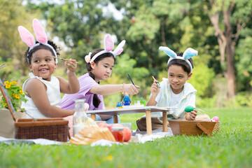 Happy family enjoying a picnic in the park, Children sitting and coloring their beautiful Easter...