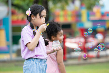 Obraz premium Girls in the park with blowing air bubble, Surrounded by greenery and nature