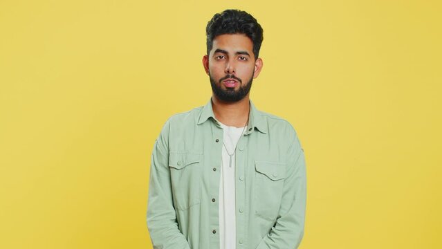 Displeased upset Indian man reacting to unpleasant awful idea, dissatisfied with bad quality, wave hand, shake head No, dismiss idea, don't like proposal. Arabian guy isolated on yellow background