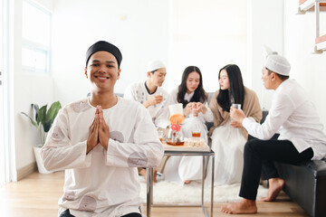 Asian moslem guy showing greeting or welcome gesture while his friends having conversation on the...