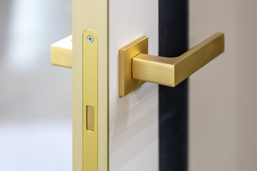 Magnetic lock on an open interior door, close-up. Silent door fittings. Golden door handle on a white interior door. Modern minimalism in design. Interior accessories for apartments or offices
