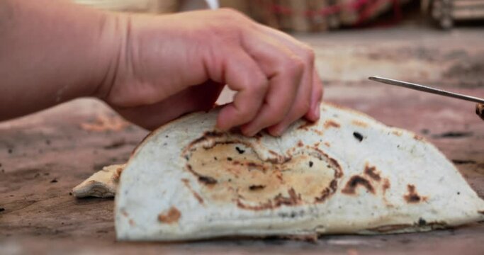  Close-up of a tlacoyo cooking on a clay comal, showing the colors and textures of this dish. The comal sits over a campfire, the unique flavor of Mexican food.