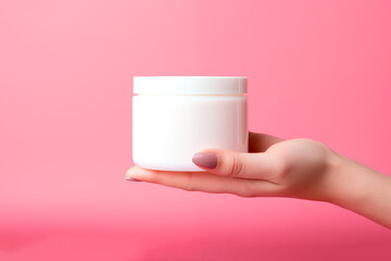 Woman hand holding blank white cosmetic jar mockup on pink background