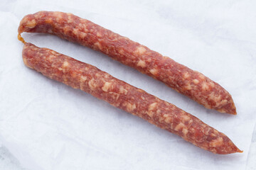 Sausages or salami on butcher paper. Pork or beef jerky. Kabanos sausage. Meat stick of Cabanos or Cabanossi Thin Dry Smoked Polish or Russian Sausage. Good for beer snack. High resolution food photo