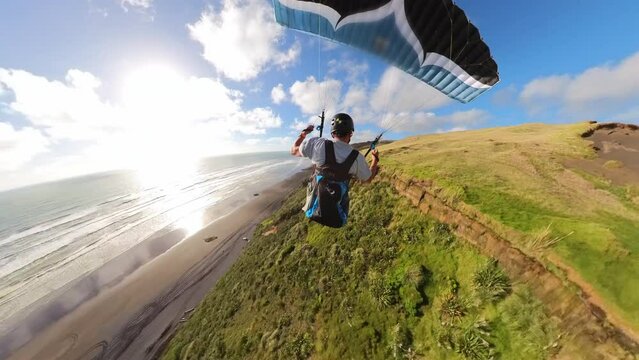Paraglider soaring fast along the New Zealand coast at sunset. Adventure, freedom, and outdoor lifestyle concept.