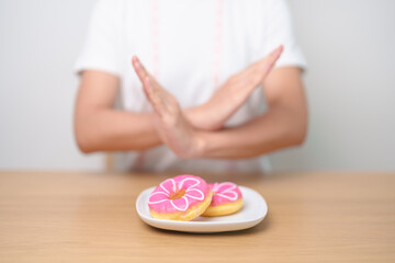 woman hand reject donut dessert, female refuse Unhealthy junk food. Dieting control, Weight loss,...
