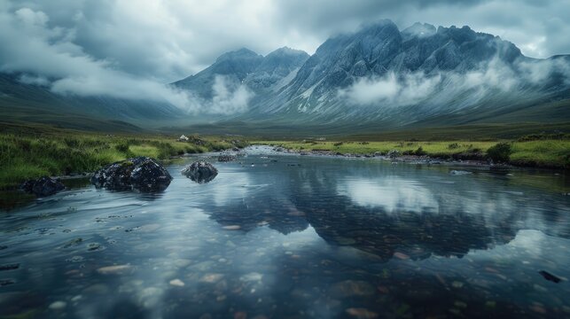 Clouds weave through the rugged mountain landscape, casting dramatic shadows over the wild terrain. The mirrored surface of a serene mountain stream captures the fleeting beauty of a moody sky