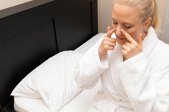 White Woman Applies Nasal Strip on Nose Before Going To Bed, Sitting on Bed. Stop Drug-free, Snoring, Sleeping Apnea Solution. Copy Space. Adhesive Bandage For Better Healthy Breathing. Horizontal.