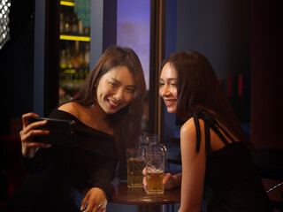 Women and friend using smart phone take a photo in nightclub