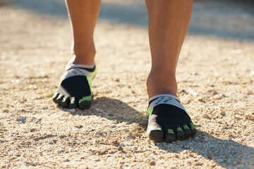 Person, runner and athlete with footwear for running, marathon or sports on dirt road or terrain....