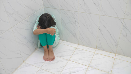 Unhappy depressed asian child sitting on floor at home. Concept for campaign against child...