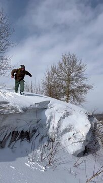 male stuntman jumps from a cliff into an abyss with snow. parkour, trick, somersault.