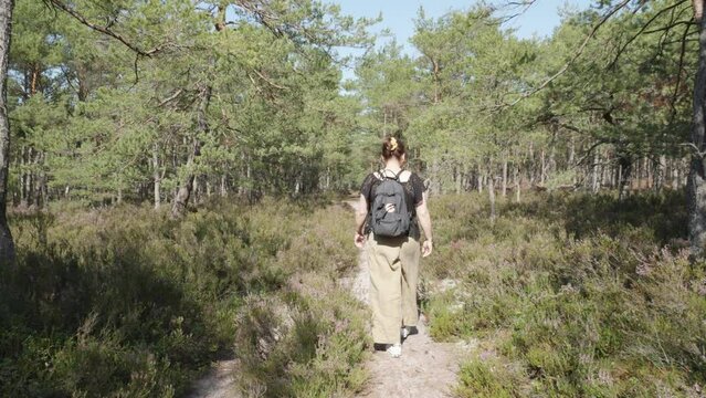 A woman wanders through a forest and heathland, with the camera following her. Filmed in Stilo, Poland.