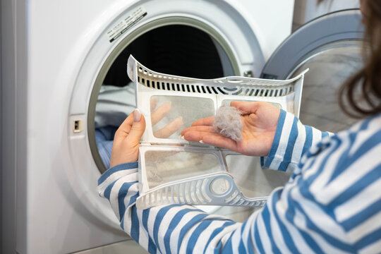 Female housewife hands cleaning filter dryer machine from wool textile fiber and particles closeup
