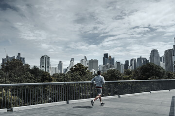 A man running up on footbridge in the city center park for cardio workout.  Health and Lifestyle in big city life concept.