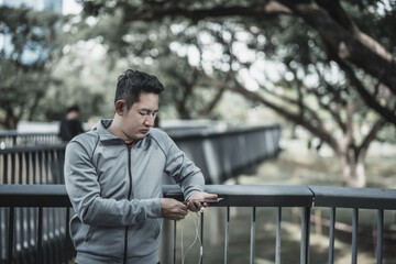 Obraz premium sport man listen music earphone and use smartphone Fitness application, social media, listening to music. Health and Lifestyle in big city life concept.