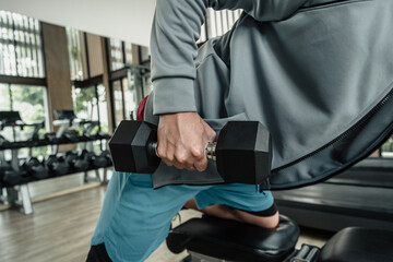 A man doing exercises triceps muscle with dumbbell in gym. Fitness, workout and traning concept.