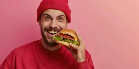 portrait of a young man eating delicious hamburger on color background, copy space