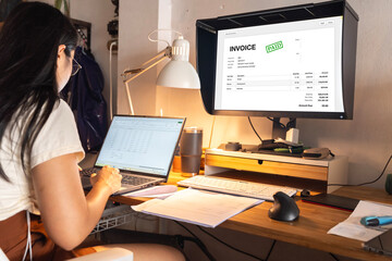 Accountant using E-invoice software at computer in office. Woman in office with sample invoice...