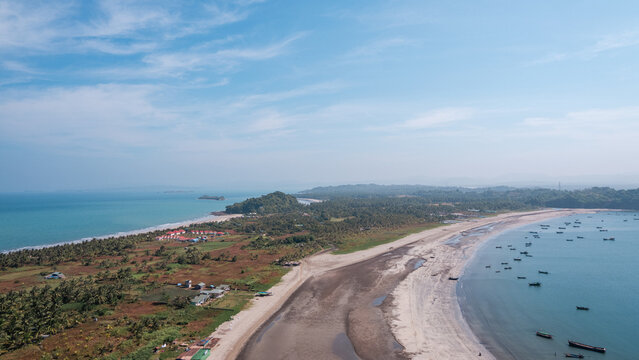 A beach with a small town in the background. Gaw Yin Gyi Island, Myanmar