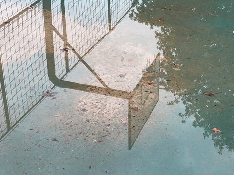 Reflection in a puddle. Basketball hoop. Wet basketball court