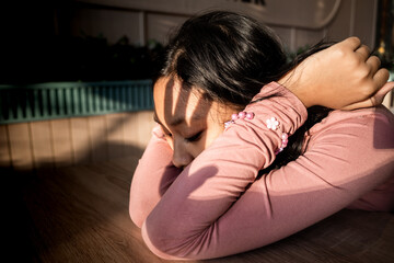 Asian  Teenage Girl with Sad Expression on Her Face and  Her Arms on Table