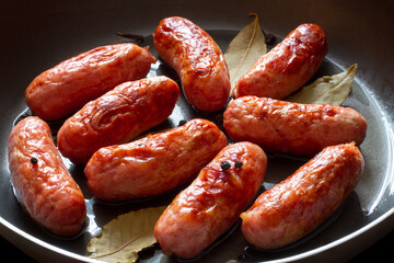 Fresh fried meat sausages close-up. Spiced sausages in a frying pan.