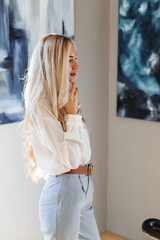 Young beautiful girl talking on the phone near the paintings