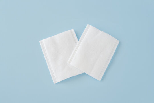 white rectangle cotton pads on blue background,  gentle and effective makeup or nail polish removal, skincare application. Soft, absorbent, hypoallergenic essentials for daily beauty routine