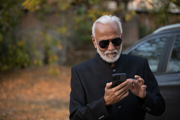 Lifestyle shot of senior Indian man wearing a suit working on a phone Digital India and digitally...