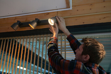 Man Changing a Burnt-Out Light Bulb on a spot light construction in an Office Ceiling Fixture