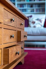 Wooden cabinet of small drawers  in a lounge setting with metal pull knobs. Stylish traditional home storage furniture. Home living  interiors design. Focus in the foreground. 