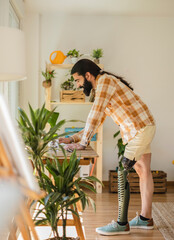man with bionic leg standing at home, looking at computer