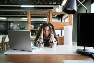 Exhausted Young Woman Feeling Overwhelmed at Her Office Desk During Work Hours