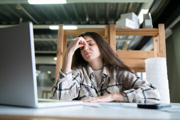 Exhausted Young Woman Feeling Overwhelmed at Her Office Desk During Work Hours