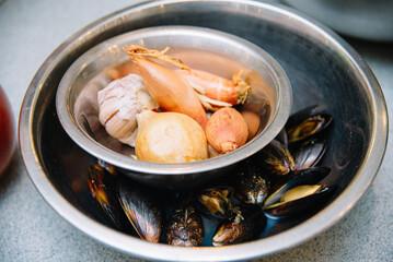 Fresh Mussels with Shallots and Garlic Prepping. A stainless steel bowl containing fresh mussels with shallots and garlic, ingredients prepped for a delicious seafood dish.