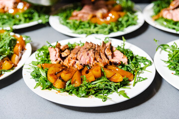 Duck Breast with Peach and Balsamic on Arugula salad. Sliced duck breast paired with caramelized peaches on a bed of arugula, drizzled with balsamic sauce.