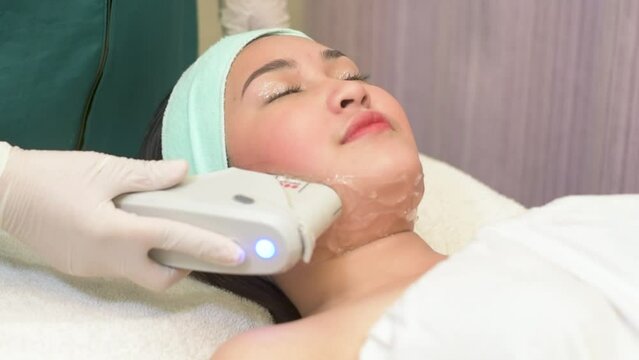 An asian woman undergoes a HIFU procedure on her jawline. A cosmetic treatment for skin tightening.