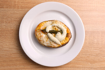 A freshly baked piece of salmon is placed on a plate and sauce is added. Cooking a fish dish.