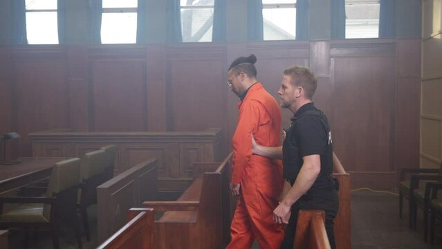 Inmate being escorted by police officer into court