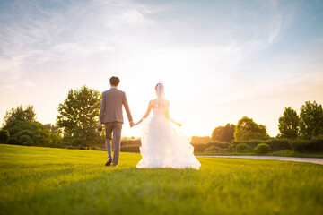 Happy bride and groom walking on the grass