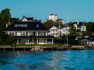Waterfront view on a white houses on a shore in Oslo fjord. Norwegian detached houses