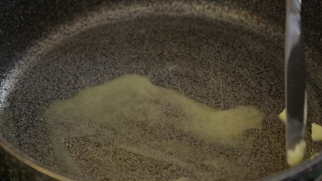Stir mmlting butter in gray frying pan skillet with butter knife
