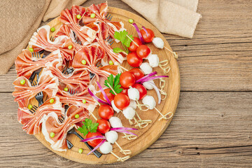 Set of picnic snacks on skewers. Jamon, mozzarella, cherry tomatoes, peas, fresh greens
