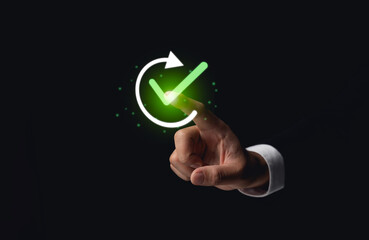 Businessman Touching Virtual Green Checkmark. Hand of a businessman interacting with a glowing green checkmark symbol on a dark background. Quality control assurance QC, QA Concept.